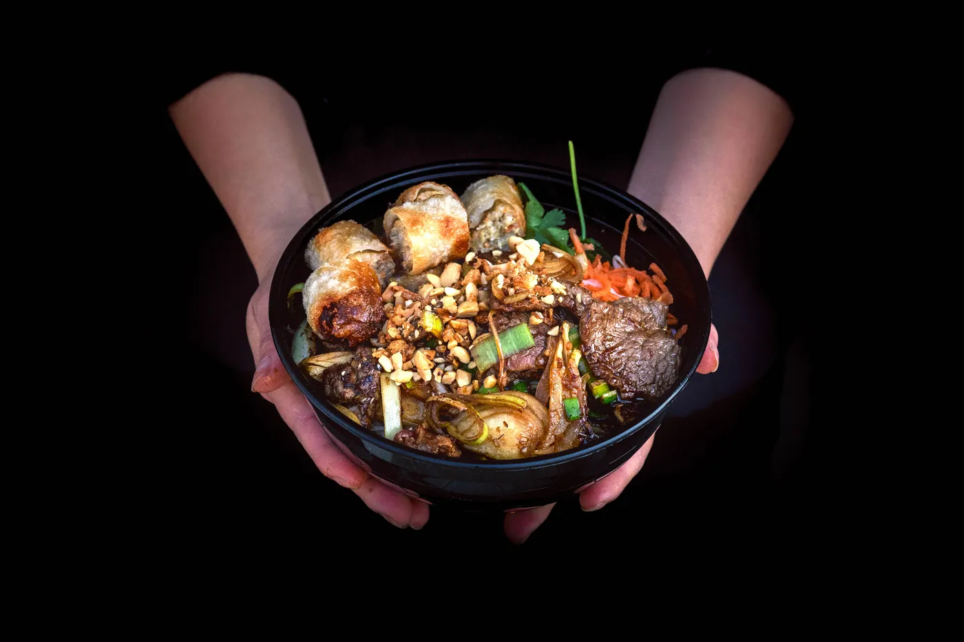 Bol de street food vietnamienne fumant tenu en mains
